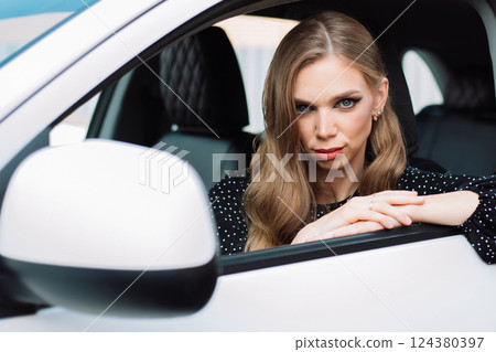 Woman with long hair sits in a white car and looks at the camera. Woman with long hair sits in a white car and looks at the camera. 124380397