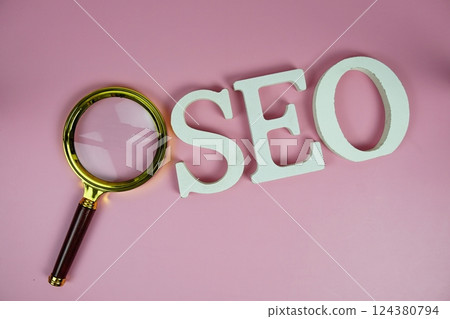 Seo words (Search Engine Optimization) letters with magnifying glass on pink background Seo words (Search Engine Optimization) letters with magnifying glass on pink background 124380794