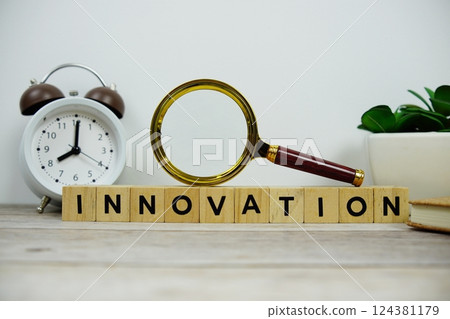 Magnifying glass and alarm clock with wooden blocks alphabet letters INNOVATION text message on wooden background Magnifying glass and alarm clock with wooden blocks alphabet letters INNOVATION text message on wooden background 124381179