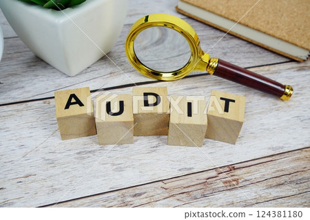 Magnifying glass with wooden blocks alphabet letters AUDIT text message on wooden background Magnifying glass with wooden blocks alphabet letters AUDIT text message on wooden background 124381180