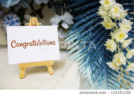 Congratulations text write on paper card with wooden easel and flowers decoration on wooden background Congratulations text write on paper card with wooden easel and flowers decoration on wooden background 124381290