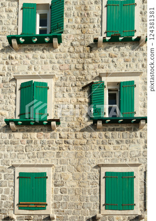 Traditional Mediterranean white stone facade with closed green wooden shutters Traditional Mediterranean white stone facade with closed green wooden shutters 124381381