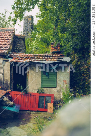 abandonen Rustic Cottage with Overgrown Greenery and Red Door abandonen Rustic Cottage with Overgrown Greenery and Red Door 124381398
