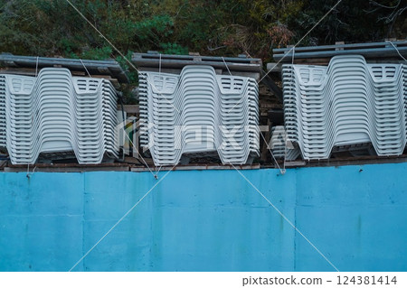 Stacked White Plastic Lounge Chairs in Storage at the End of the Season on the Mediterranean Coast Stacked White Plastic Lounge Chairs in Storage at the End of the Season on the Mediterranean Coast 124381414