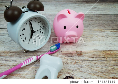 White tooth model with toothbrus, alarm clock and piggy bank on wooden background, dental hygiene concept White tooth model with toothbrus, alarm clock and piggy bank on wooden background, dental hygiene concept 124381445