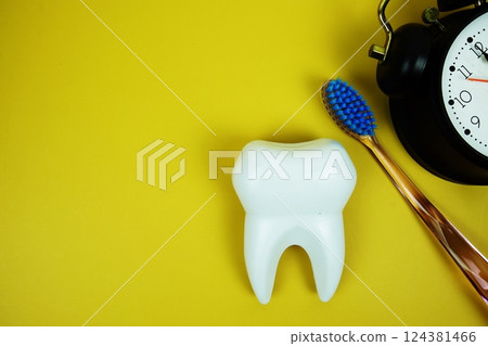 Toothbrush and White Tooth model with alarm clock dental hygiene concept on yellow background 124381466
