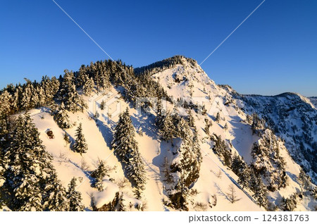 The snowy landscape of the Kuroboyama mountain ridge dyed in the morning glow 124381763