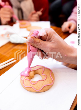 Female decorating pink icing cookie with piping bag at baking class 124382986