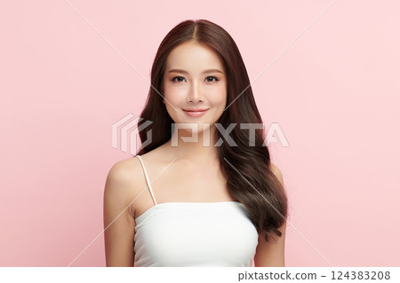 A beautiful young Asian woman with clean, fresh skin against a pink background. Skincare, facial treatment, cosmetology, beauty, and spa. An elegant portrait of an Asian woman. 124383208