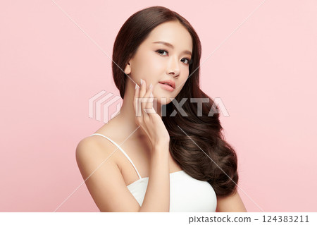 A beautiful young Asian woman with clean, fresh skin against a pink background. Skincare, facial treatment, cosmetology, beauty, and spa. An elegant portrait of an Asian woman. 124383211