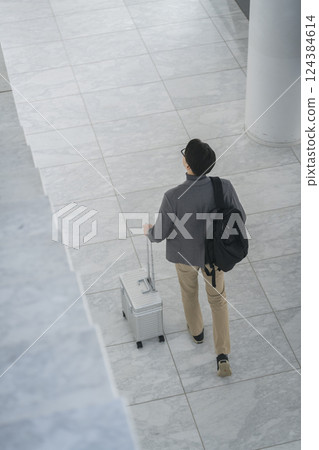 A man in his 40s walking with a carry bag, back view 124384614