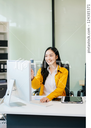Business woman using tablet and laptop for doing math finance on an office desk, 124385371