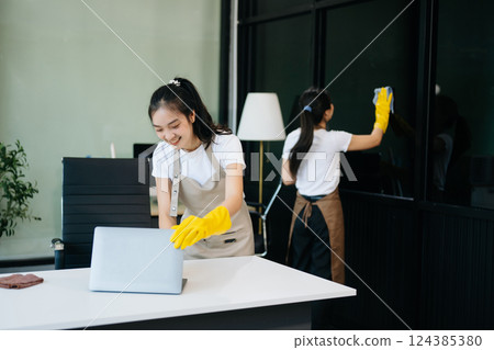 Two professional cleaners tidying a stylish space with a smile. Experience efficient and friendly house cleaning 124385380