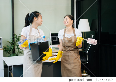 Two professional cleaners tidying a stylish space with a smile. Experience efficient and friendly house cleaning Two professional cleaners tidying a stylish space with a smile. Experience efficient and friendly house cleaning 124385402