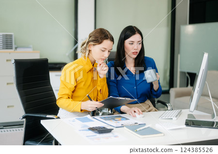 Two business workers talking on the smartphone and using laptop at the office. Two business workers talking on the smartphone and using laptop at the office. 124385526