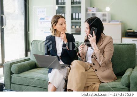Two businesswomen collaborate using a tablet in a stylish office setting. Perfect for concepts Two businesswomen collaborate using a tablet in a stylish office setting. Perfect for concepts 124385529