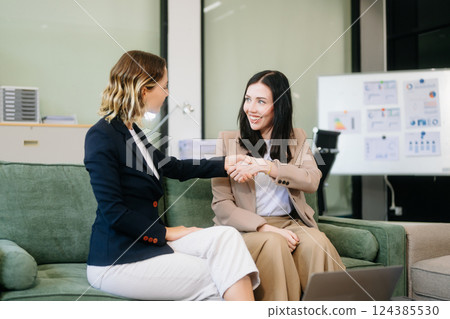 Two businesswomen strategizing with a tablet in a professional office. Highlight teamwork, leadership, Two businesswomen strategizing with a tablet in a professional office. Highlight teamwork, leadership, 124385530