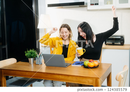 Modern couple collaborating over coffee in a cozy kitchen setting with a laptop, notebook, and breakfast. 124385579