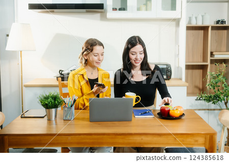 Caucasian Teamwork and creativity with sitting working at kitchen table young collaborating Caucasian Teamwork and creativity with sitting working at kitchen table young collaborating 124385618