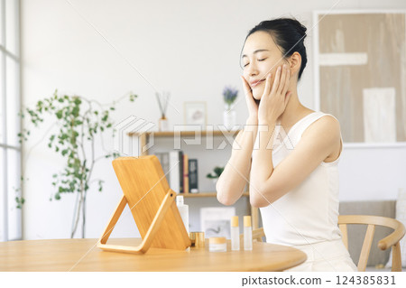 生活方式:一位女士一邊照鏡子一邊進行皮膚護理 生活方式:一位女士一邊照鏡子一邊進行皮膚護理 124385831