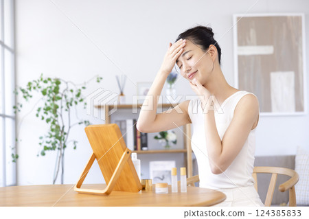 Lifestyle: A woman doing skin care while looking in the mirror Lifestyle: A woman doing skin care while looking in the mirror 124385833