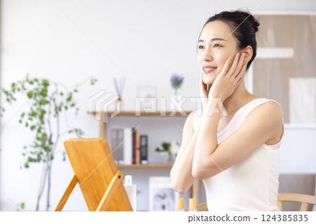 Lifestyle: A woman doing skin care while looking in the mirror 124385835