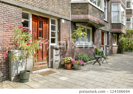 A welcoming entrance featuring a blend of vibrant plants and a cozy seating area, set within a stylish brick building. 124386694
