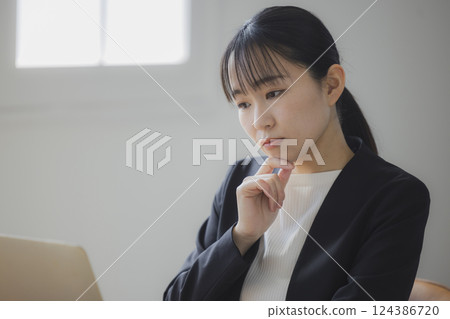 女商人一邊看著電腦螢幕一邊思考 124386720