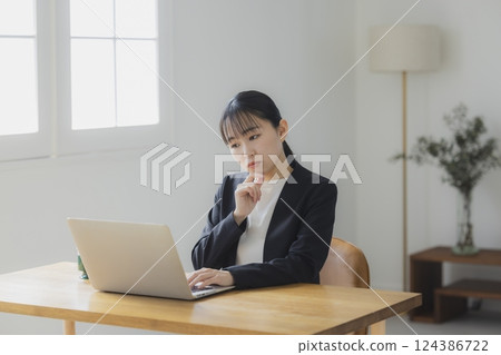 Businesswoman thinking while looking at a computer screen 124386722