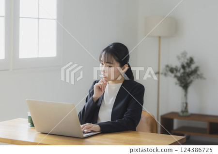 Businesswoman thinking while looking at a computer screen Businesswoman thinking while looking at a computer screen 124386725