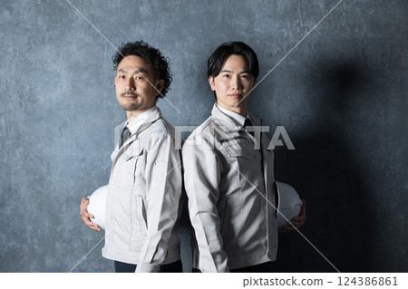 A man in work clothes with his arms folded and a fist pump expression, industrial image of construction management, factory, etc., looking at the camera 124386861