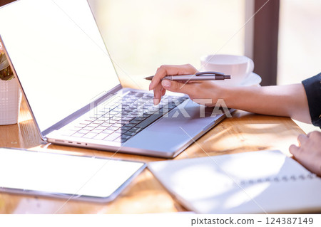 Hand of a businesswoman standing working with a laptop in the office. Hand of a businesswoman standing working with a laptop in the office. 124387149