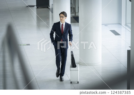 A businessman in his 40s walking with a suitcase A businessman in his 40s walking with a suitcase 124387385