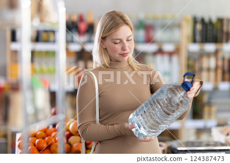 Young woman choosing water in grocery store Young woman choosing water in grocery store 124387473