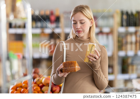 Young woman choosing cheese in grocery store Young woman choosing cheese in grocery store 124387475