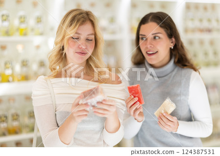 Two female friends choose scented handmade soap together in perfume shop 124387531
