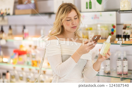 Girl takes pictures of perfume bottle in store 124387540