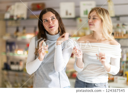 Two girls friends are in perfume store buying perfumes Two girls friends are in perfume store buying perfumes 124387545