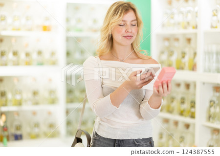 Young woman scanning qr code for eau de toilette Young woman scanning qr code for eau de toilette 124387555