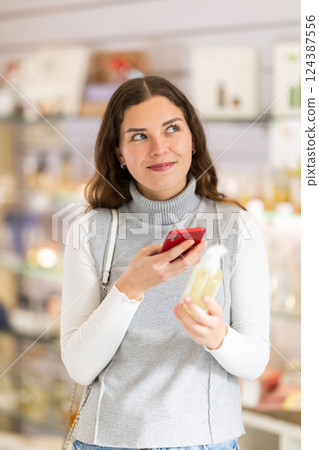 Female shopper scanning QR code on perfume in perfume shop Female shopper scanning QR code on perfume in perfume shop 124387556