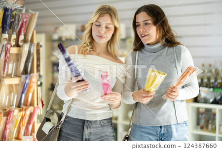 Two friends choose scented candles and sticks in perfume shop 124387660