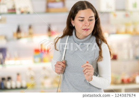 Girl is looking for something in perfume shop. Large selection of perfumes and cosmetics 124387674