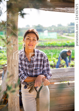 Girl in white jeans on veranda with shovel on background of garden beds Girl in white jeans on veranda with shovel on background of garden beds 124387675