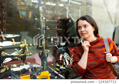 Woman tourist choosing handmade swords 124387713