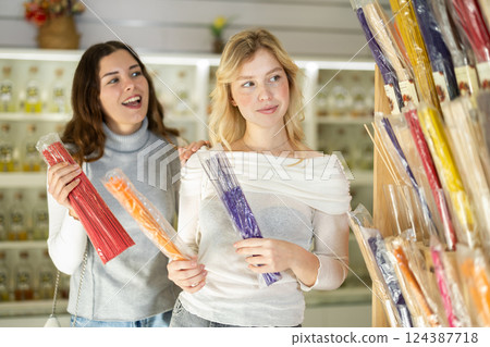 Young woman seller offers incense sticks to woman buyer 124387718