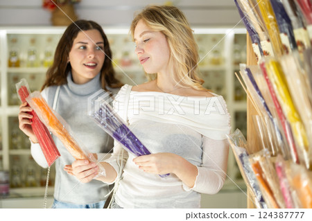 Young woman seller offers incense sticks to woman buyer 124387777