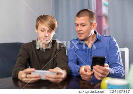 Boy with father resting and playing on phone Boy with father resting and playing on phone 124387817