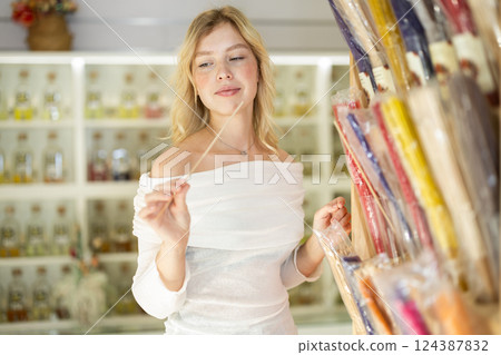 Young woman choosing incense sticks in store Young woman choosing incense sticks in store 124387832