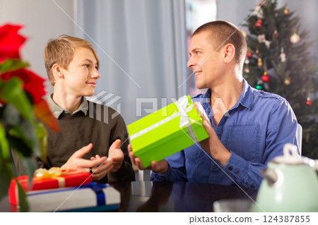 Father and son give each other christmas gifts in home Father and son give each other christmas gifts in home 124387855