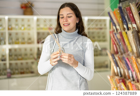 Happy girl holding incense sticks while deciding which ones to buy 124387889